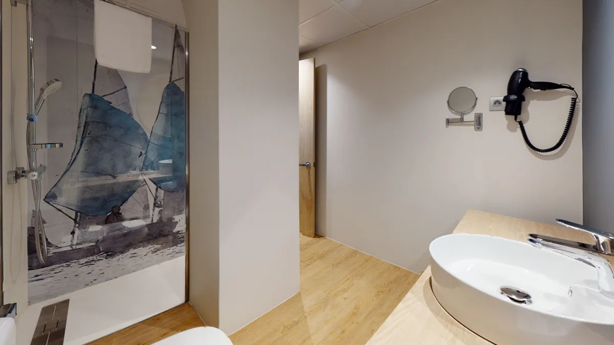 Baño del Barceló Occidental Alicante con un velero impreso en la pared de la ducha