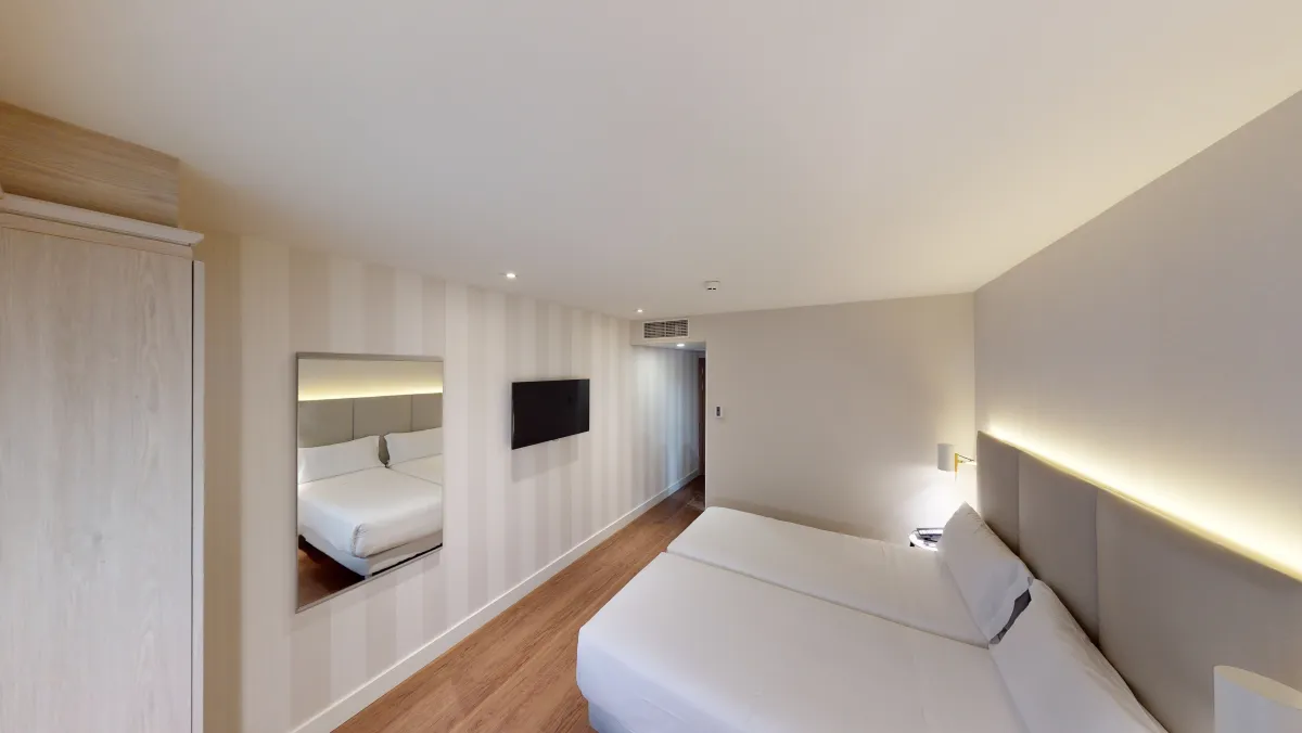 Habitación del NH Madrid Barajas con cabecero iluminado y pared de rayas