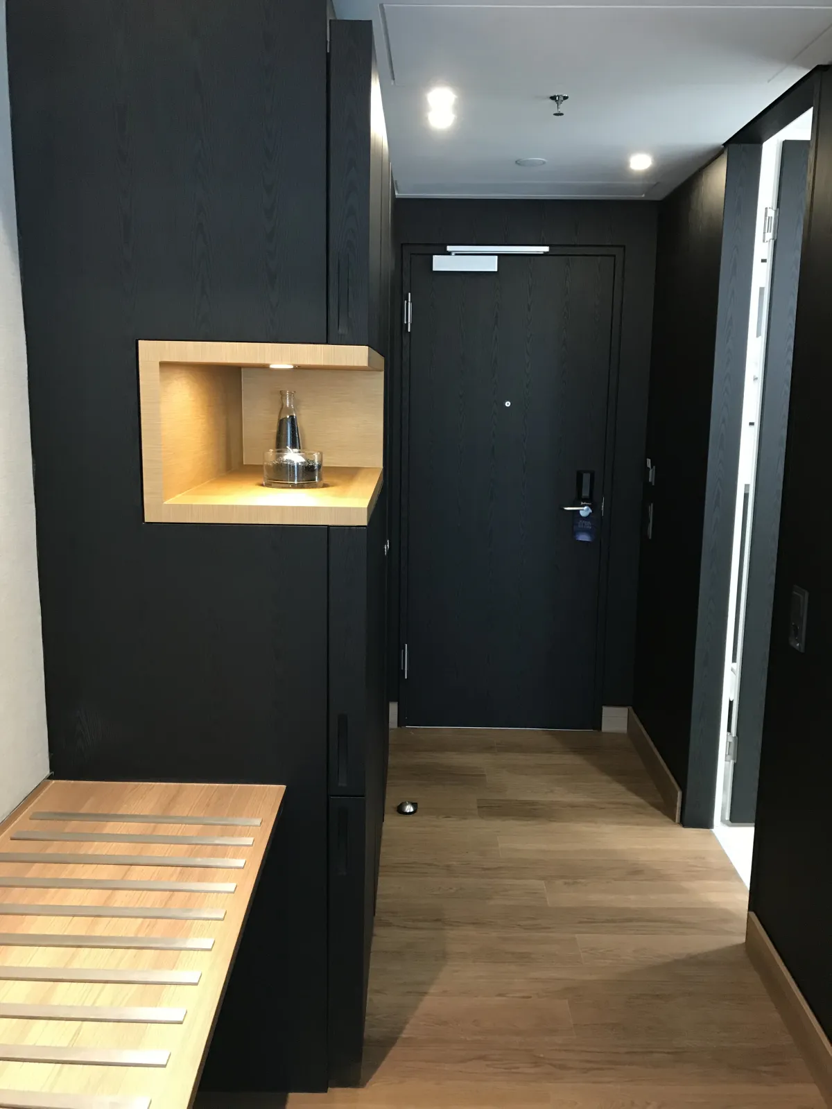 Entrada de una habitación del Radisson Blu Colonia, con armario negro y una hornacina de madera