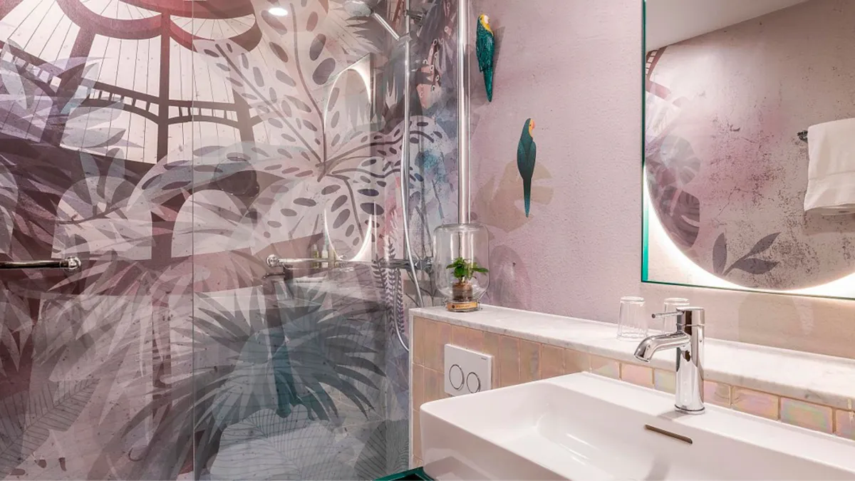 Baño del Hotel Indigo Bruselas con una imagen de hojas tropicales en la pared