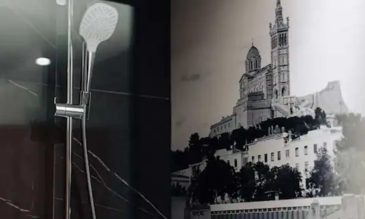 Ducha del Radisson Blu Marsella junto a un fotomural en blanco y negro de una basílica sobre la ciudad